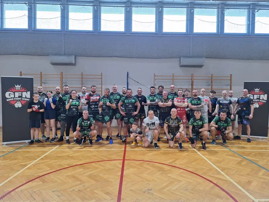 Kilkadziesiąt osób w hali sportowej między banerami Gros Fight Night